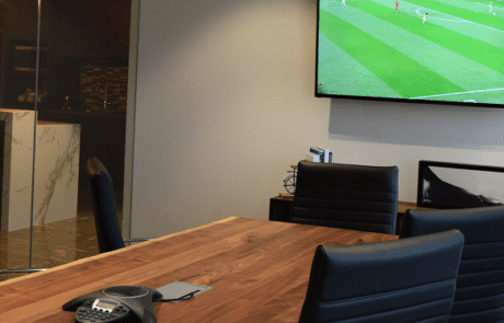 Modern conference room with a TV showing soccer.