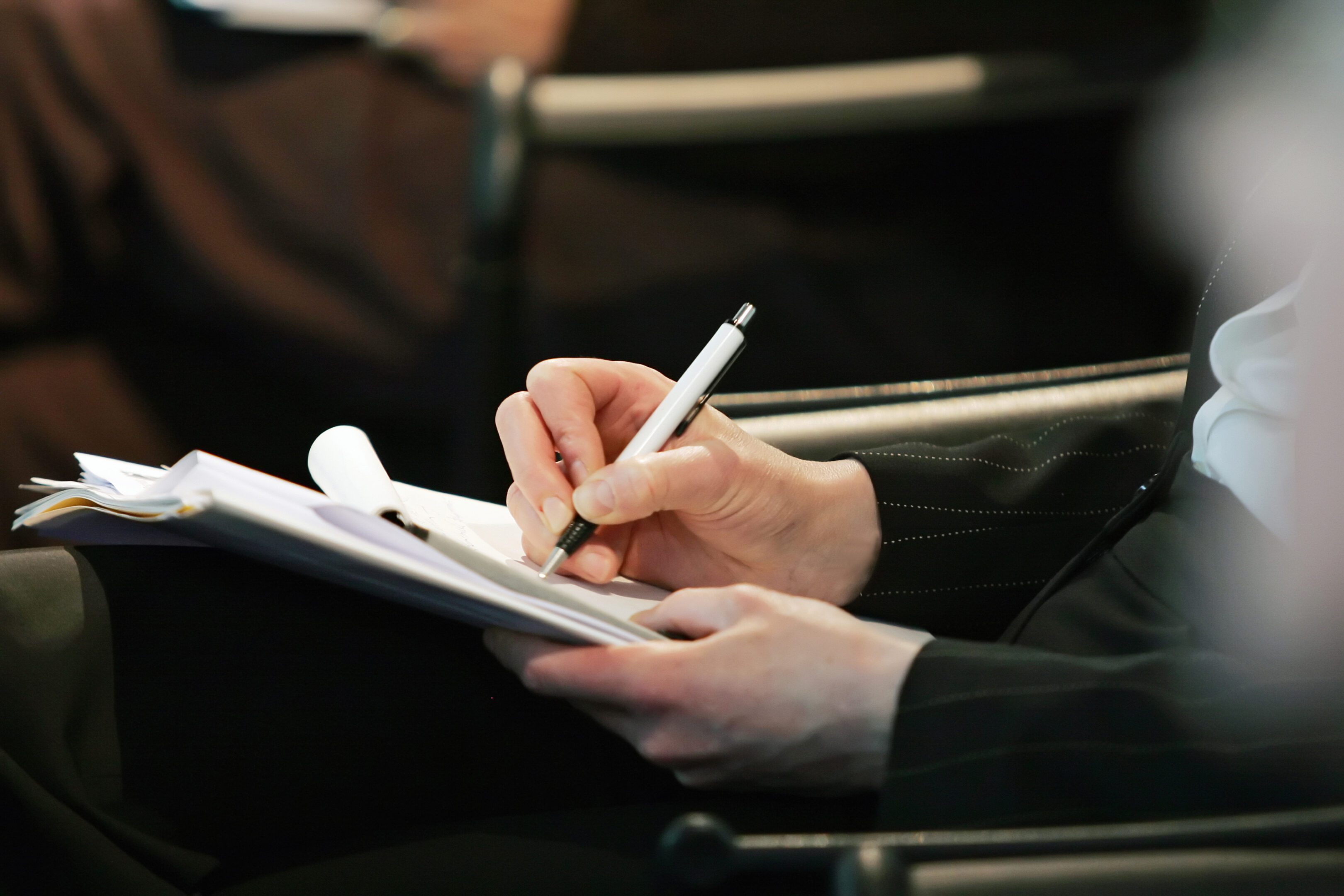 A person writing on paper with a pen.